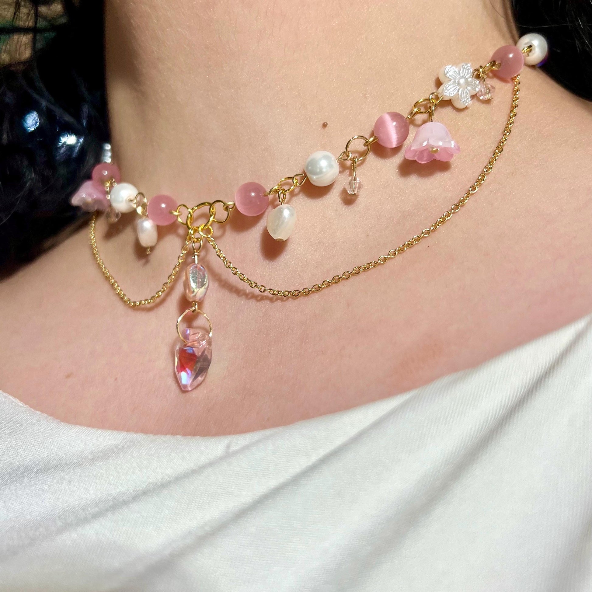 Model wearing Glinda-inspired fairycore choker necklace with adjustable gold-plated chain, featuring pink and pearl accents, flowers, and heart charms