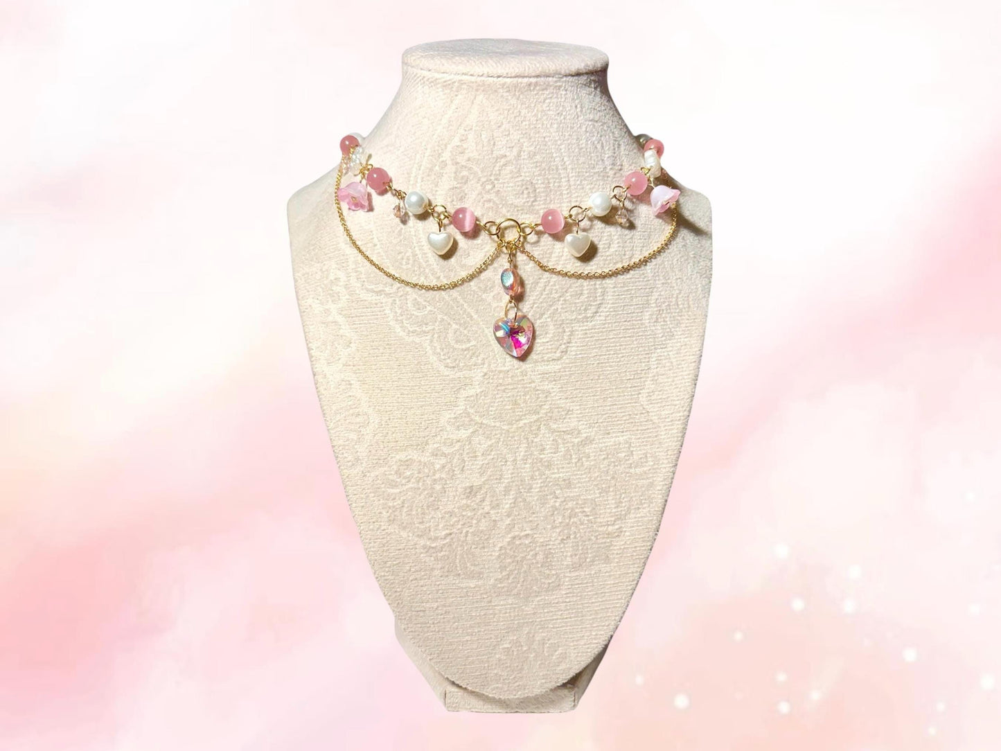 Handmade fairycore choker necklace with pink beads, faux pearls, gold-plated chain, heart-shaped charms, and flower accents, inspired by Glinda from Wicked